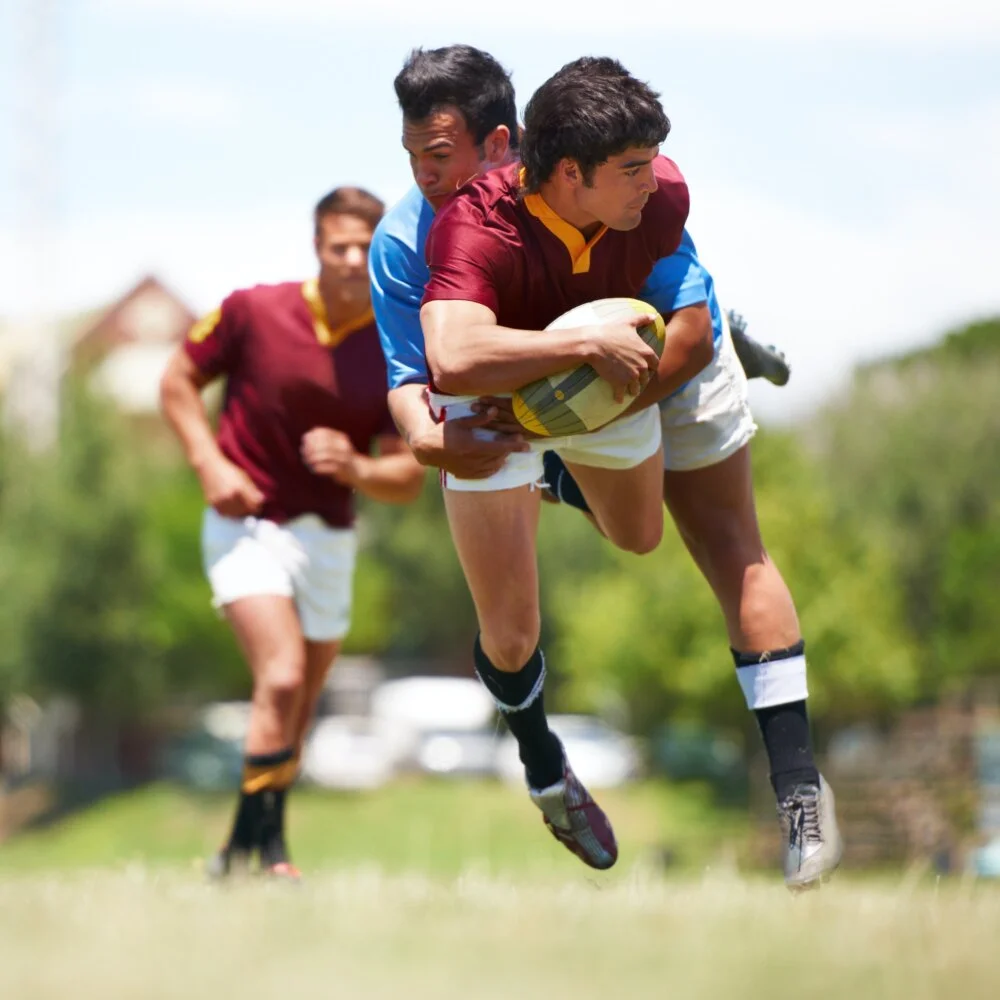 A young rugby player trying to avoid a tackle.